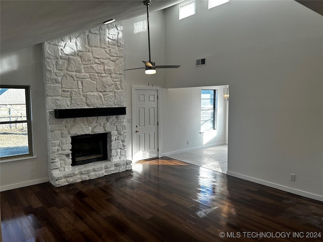 unfurnished living room with high vaulted ceiling, a stone fireplace, and dark hardwood / wood-style floors