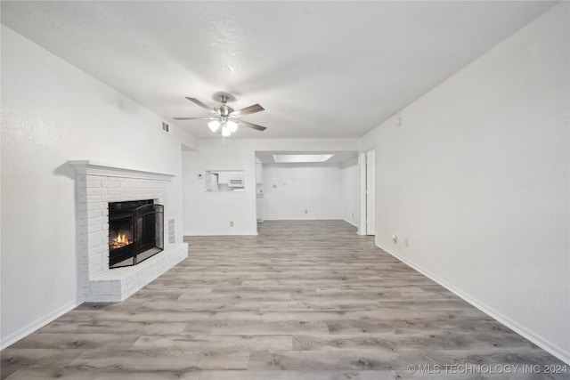 unfurnished living room with ceiling fan, light hardwood / wood-style floors, and a brick fireplace