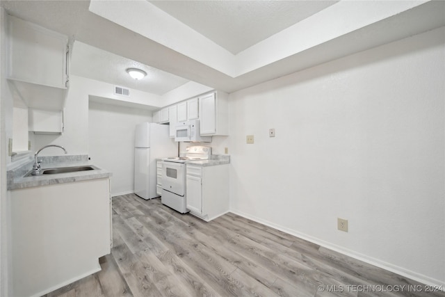 kitchen featuring white appliances, white cabinets, sink, a textured ceiling, and light hardwood / wood-style floors