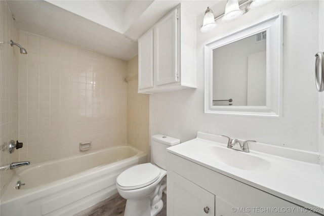 full bathroom featuring hardwood / wood-style flooring, vanity, toilet, and tiled shower / bath