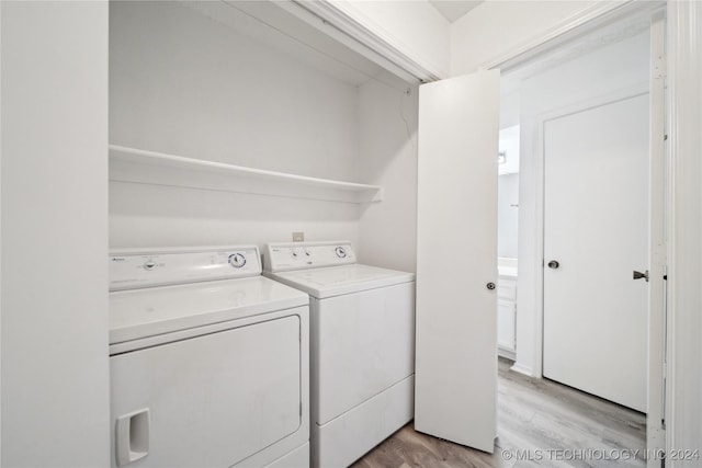 washroom with washing machine and dryer and light hardwood / wood-style flooring