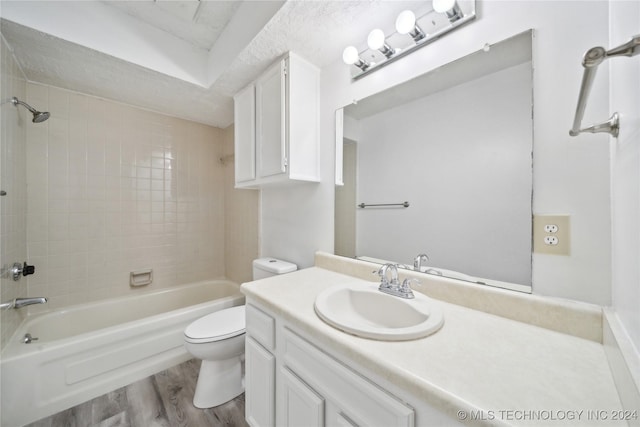 full bathroom featuring vanity, tiled shower / bath combo, toilet, a textured ceiling, and wood-type flooring