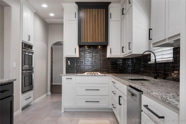 kitchen with sink, tasteful backsplash, light stone counters, white cabinetry, and stainless steel appliances