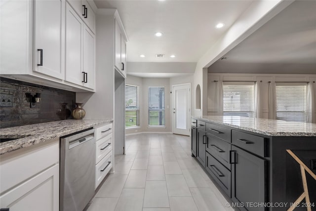 kitchen featuring dishwasher, decorative backsplash, light stone countertops, light tile patterned floors, and white cabinetry