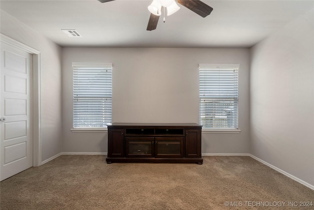 carpeted spare room featuring plenty of natural light and ceiling fan