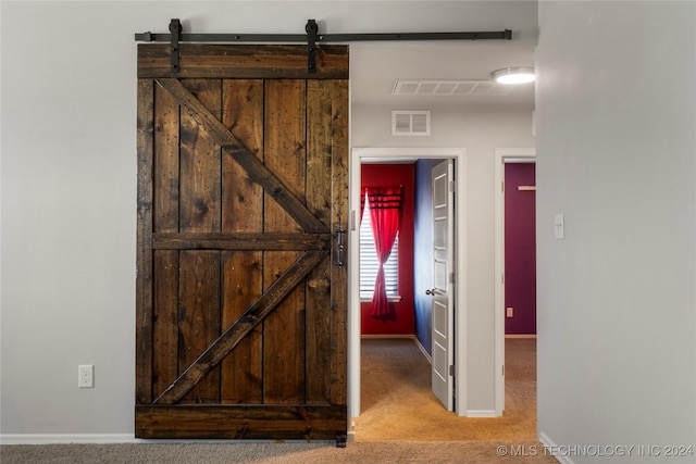 hallway featuring a barn door and light carpet