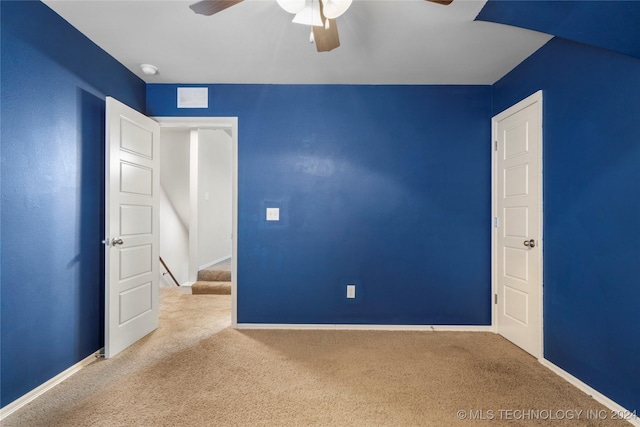 empty room featuring ceiling fan and light colored carpet