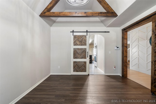 interior space featuring vaulted ceiling with beams, a barn door, and dark hardwood / wood-style flooring