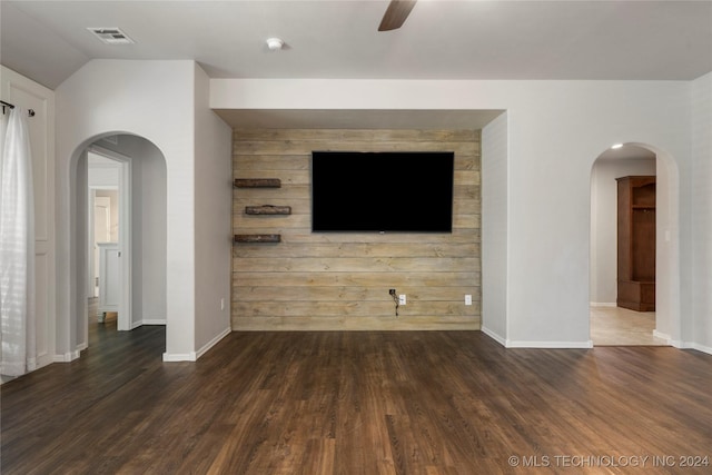 unfurnished living room featuring vaulted ceiling, ceiling fan, dark hardwood / wood-style flooring, and wood walls