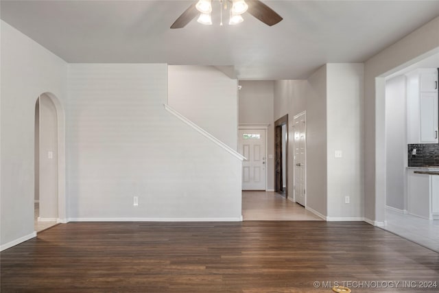 unfurnished living room with ceiling fan and dark wood-type flooring