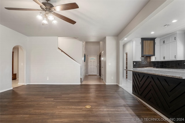 kitchen featuring stone counters, ceiling fan, dark hardwood / wood-style flooring, backsplash, and white cabinets