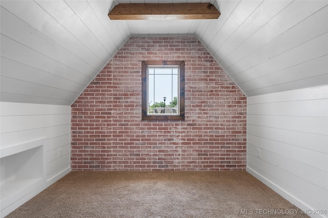 bonus room featuring carpet, vaulted ceiling with beams, wooden walls, and brick wall