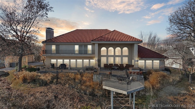 back house at dusk with a balcony