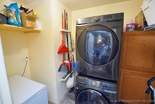 clothes washing area with hardwood / wood-style flooring and stacked washer / dryer