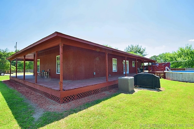 view of side of home with a swimming pool side deck, a yard, and central air condition unit