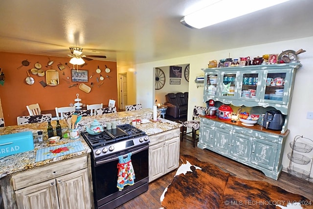 kitchen with white cabinetry, ceiling fan, light stone countertops, dark hardwood / wood-style floors, and stainless steel range with gas stovetop