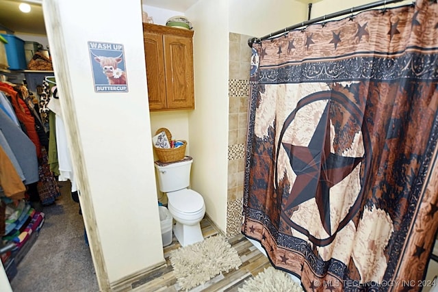 bathroom with hardwood / wood-style floors, curtained shower, and toilet