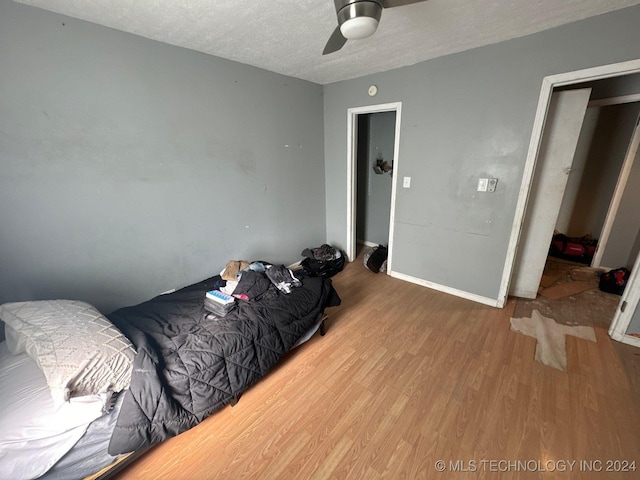 bedroom with ceiling fan, hardwood / wood-style floors, and a textured ceiling