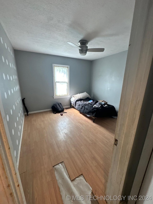 bedroom featuring hardwood / wood-style floors, ceiling fan, and a textured ceiling