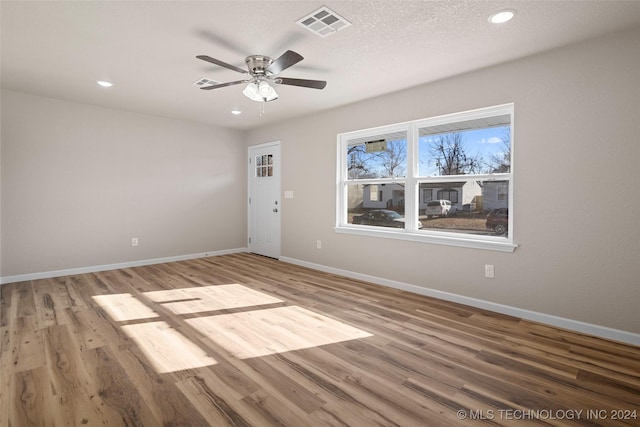 spare room with hardwood / wood-style floors, ceiling fan, and a textured ceiling