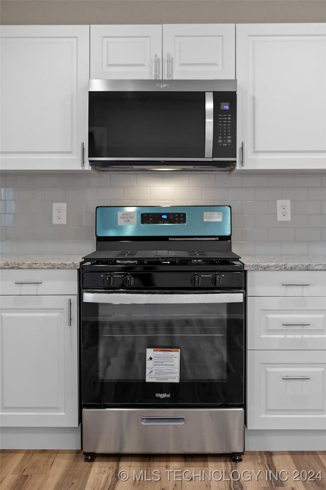 kitchen featuring backsplash, light stone countertops, white cabinets, and stainless steel appliances