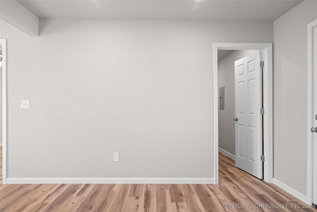 spare room with electric panel and light hardwood / wood-style flooring