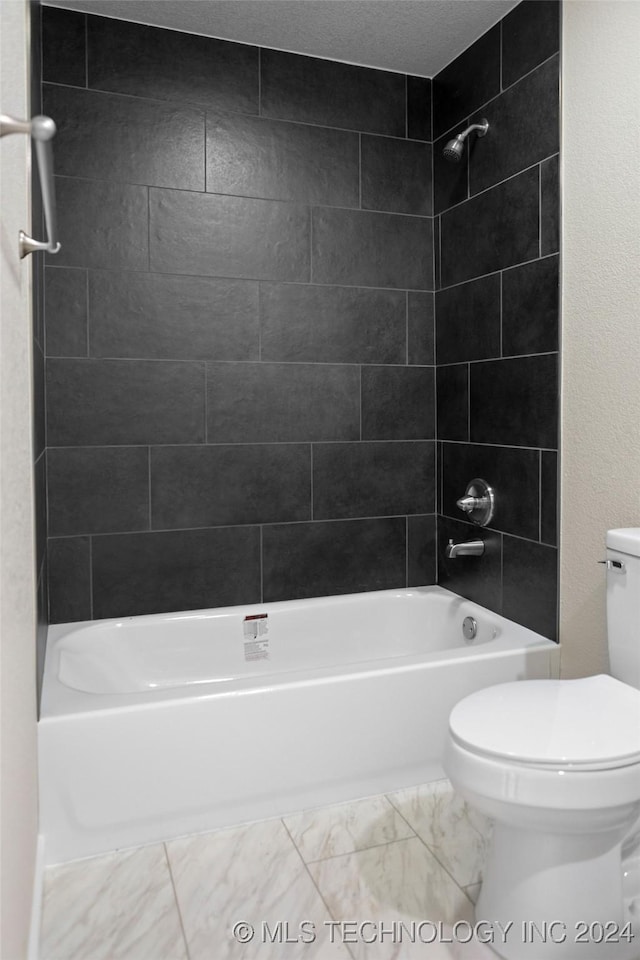 bathroom featuring a textured ceiling, tiled shower / bath combo, and toilet