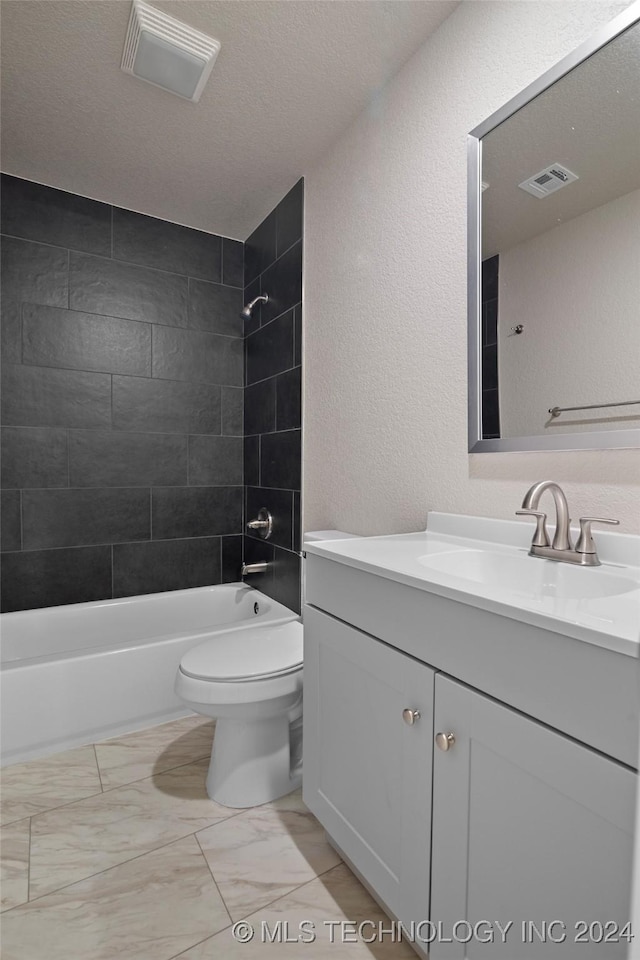 full bathroom with a textured ceiling, vanity, toilet, and tiled shower / bath