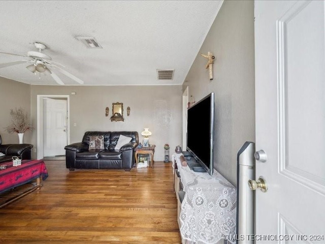 living room featuring hardwood / wood-style flooring, ceiling fan, and a textured ceiling