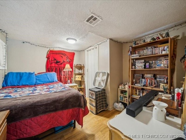 bedroom with a textured ceiling and hardwood / wood-style flooring