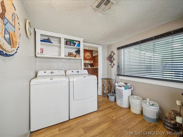 washroom with light hardwood / wood-style floors, a textured ceiling, and independent washer and dryer