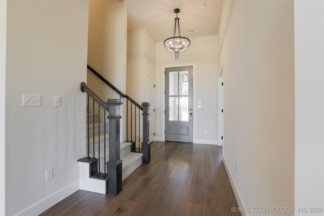 foyer with dark wood-type flooring and a chandelier