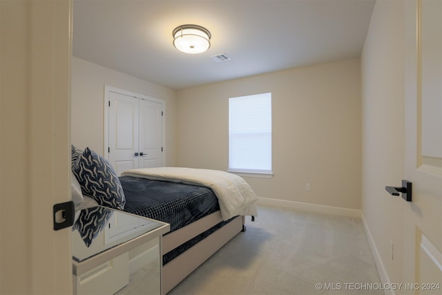 bedroom featuring visible vents, baseboards, light colored carpet, and a closet