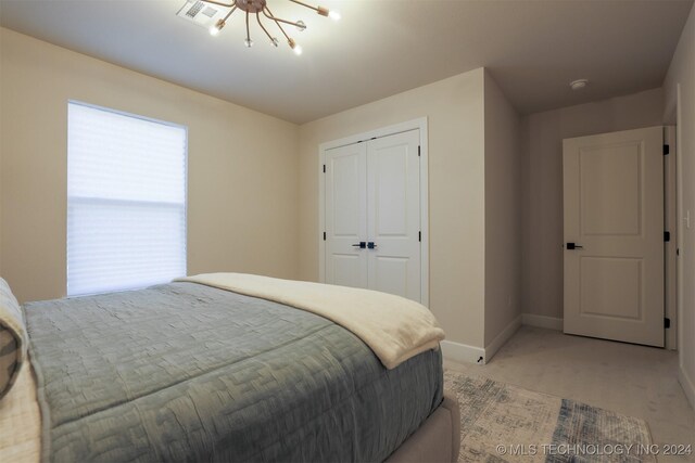 bedroom with light carpet, a closet, and a notable chandelier