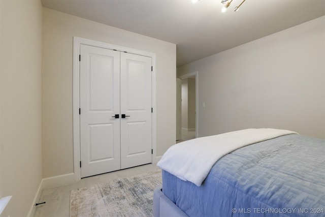 bedroom featuring a closet, light carpet, and baseboards