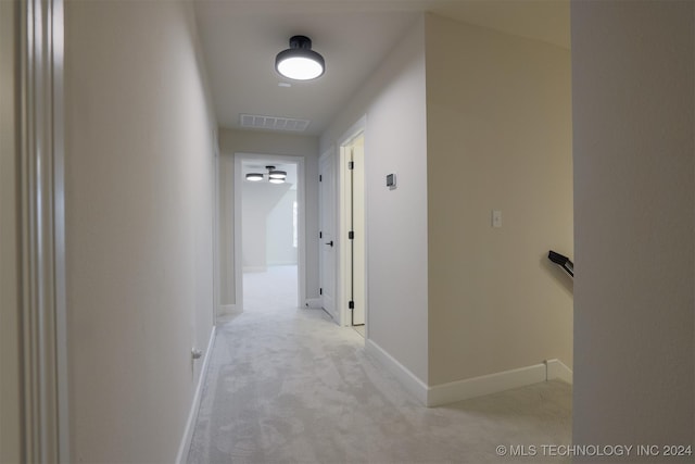 corridor featuring baseboards, an upstairs landing, light colored carpet, and visible vents