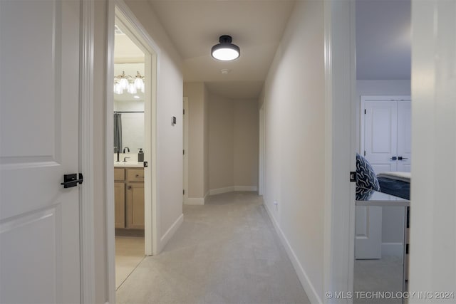 corridor featuring light colored carpet, baseboards, and a sink