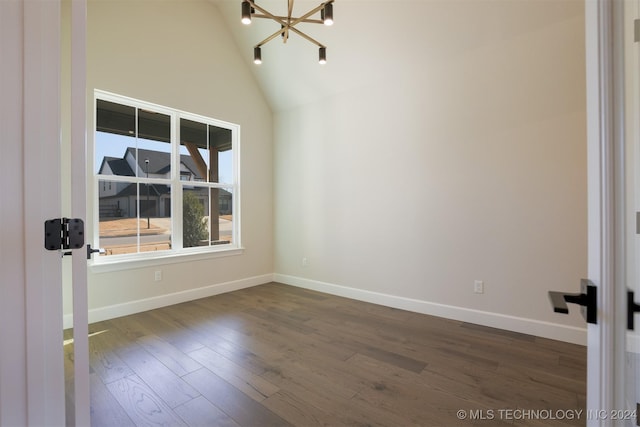 spare room featuring a notable chandelier, dark wood-style floors, baseboards, and high vaulted ceiling