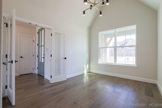 unfurnished bedroom featuring dark wood finished floors, a chandelier, high vaulted ceiling, and baseboards