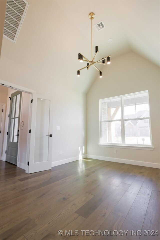 unfurnished living room featuring a chandelier, dark hardwood / wood-style flooring, and vaulted ceiling