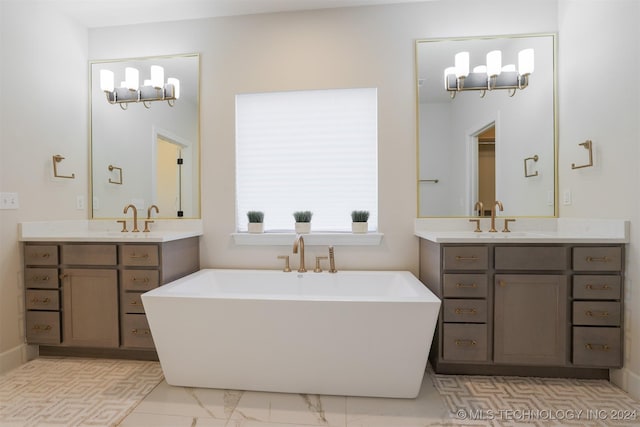 full bath with marble finish floor, a freestanding bath, and a sink