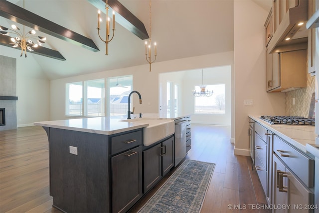 kitchen featuring pendant lighting, a kitchen island with sink, sink, a fireplace, and beam ceiling