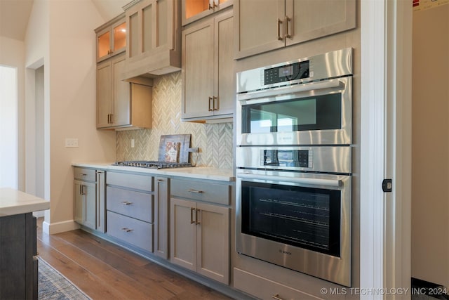 kitchen with light brown cabinets, dark hardwood / wood-style flooring, backsplash, premium range hood, and appliances with stainless steel finishes