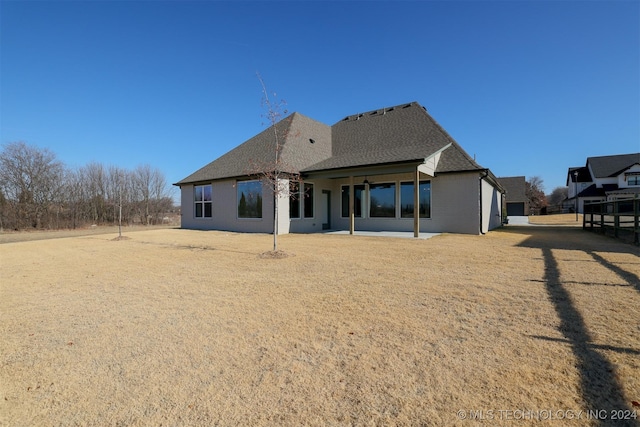 back of house featuring a patio and roof with shingles