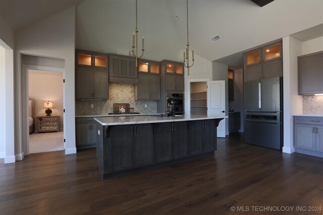 kitchen with a large island, decorative light fixtures, stainless steel appliances, and high vaulted ceiling