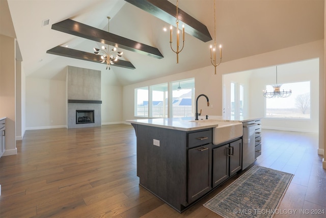 kitchen featuring beam ceiling, sink, a wealth of natural light, and an island with sink