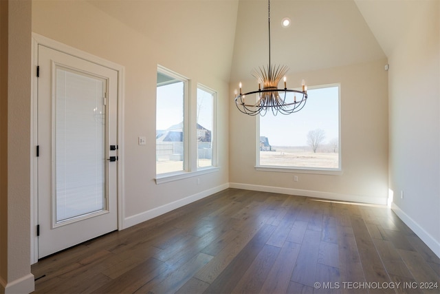 unfurnished dining area featuring high vaulted ceiling, dark wood-style floors, baseboards, and a chandelier