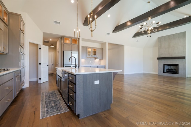 kitchen with vaulted ceiling with beams, a center island with sink, dark wood-type flooring, and a fireplace