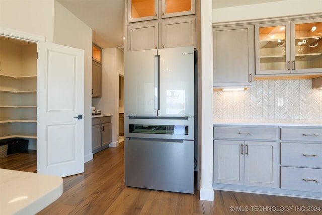 kitchen featuring dark hardwood / wood-style floors, decorative backsplash, and stainless steel refrigerator