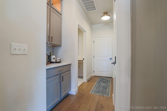 hall with visible vents, baseboards, and wood finished floors